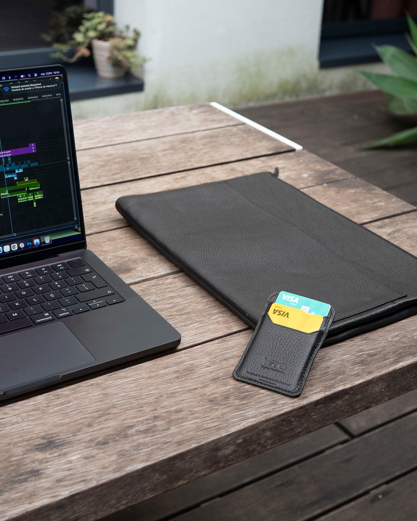 LGDO leather laptop sleeve and cardholder on wooden desk next to open MacBook, everyday work setup